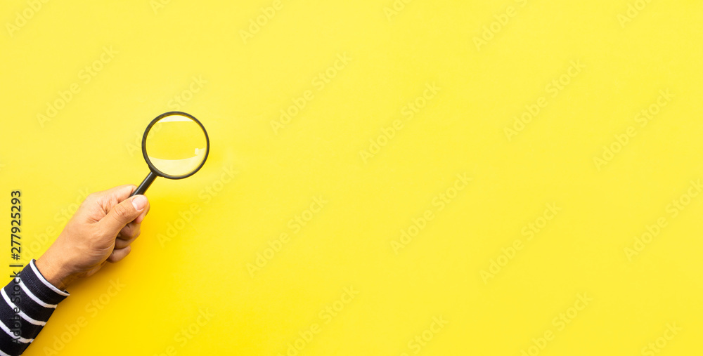 Searching concepts with male hand using magnifying glass on yellow space background - obrazy, fototapety, plakaty 