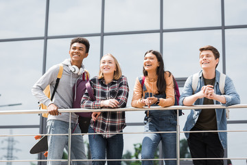 Wall Mural - cheerful and happy teenagers smiling and looking away outside