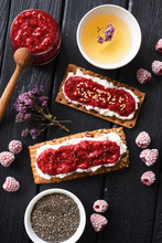 Healthy Sugar Free Dessert And Herbal Tea. Raspberry Chia Jam On Crispy Bread And Cream Cheese With Frozen Berries On Black Background