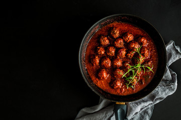 Wall Mural - Meatballs in tomato sauce on the pan - black background