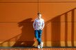 © Cavan Images - Front view young man leaning on a wall while looking away