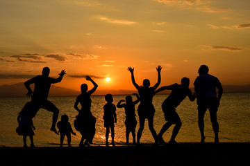 silhouette of friends jumping on beach during sunset time