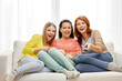 © Syda Productions - entertainment, leisure and friendship concept - three smiling teenage girls or friends with popcorn and remote watching tv at home