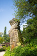 Large Rock Boulder against a natural blue sky surrounded by lush green trees in Derbyshire, UK
