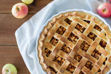 Wall Mural - food, culinary and baking concept - apple pie and kitchen towel on wooden table