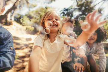Poster - Girl with friends catching the soap bubbles