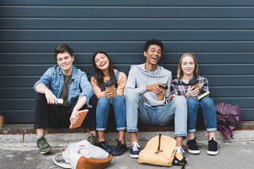 Wall Mural - happy teenagers sitting, smiling, holding paper cups and looking at camera