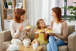 © Syda Productions - family, generation and food concept - smiling mother, daughter and grandmother having tea party and eating cake at home