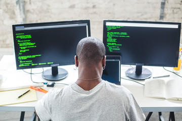 High angle view of shaved head computer programmer programming codes at desk in office