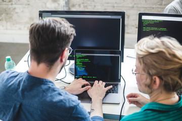 High angle view of computer programmers coding in laptop at desk