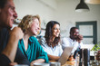 © Maskot - Smiling professional hackers looking away while sitting at table in start-up office
