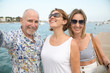 © NomadCam - Portrait of two happy women and an older man over seaside promenade taking selfie