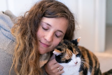 Closeup Portrait Of Happy Smiling Young Woman Bonding With Calico Cat Pet Companion, Bumping Rubbing Bunting Heads, Friends Showing Affection