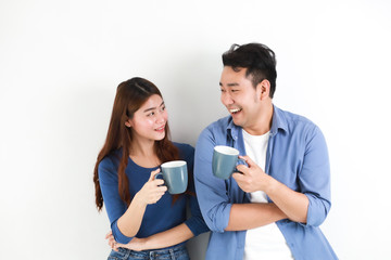 Wall Mural - Asian couple in blue shirt on white background with cup of coffee happy and smile mood