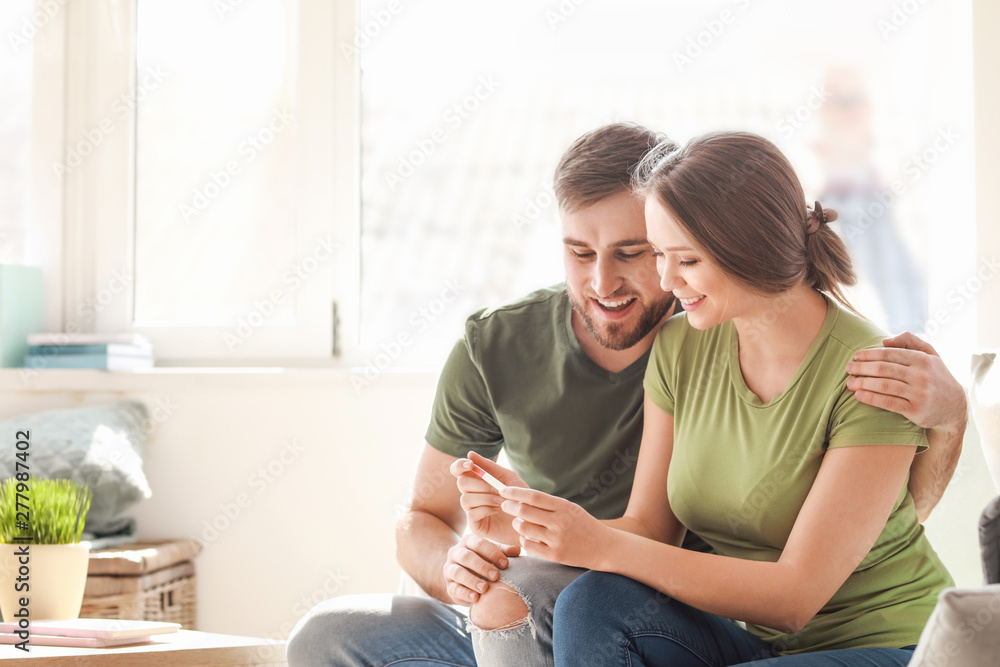 Happy couple with pregnancy test at home