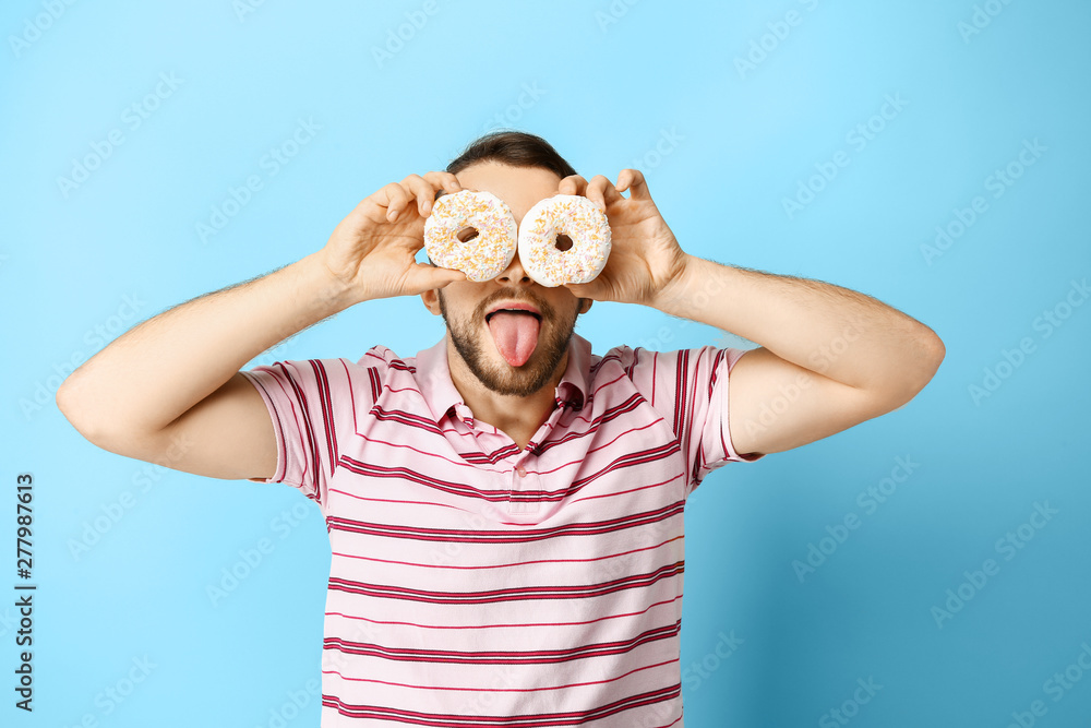 Funny man with donuts on color background