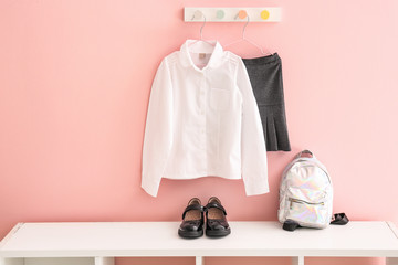 Stylish school uniform with backpack and shoes in room