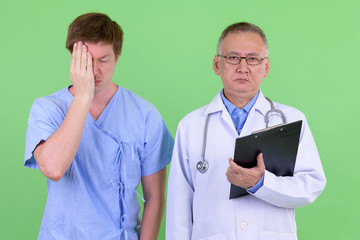 Mature Japanese man doctor with Scandinavian man patient getting bad news together