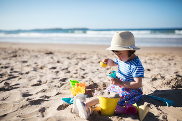 Wall Mural - toddler girl plaiying at summer sand beach,Northern Ireland