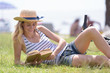 woman reading book on grass with glass and hat