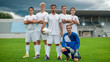 © Gorodenkoff - Professional Soccer Players Team Posing for a Group Photo Standing on a Football Field, Goalkeeper Sitting and Smiling.