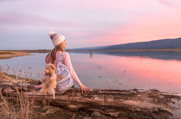 Relaxed woman watching a serene sunset by the lake