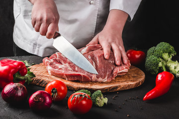 Wall Mural - Chef Butcher cutting pork meat with knife on kitchen, cooking food