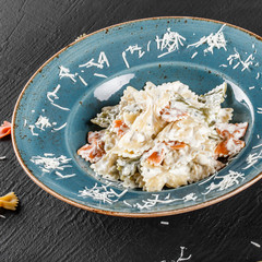 Wall Mural - Farfalle pasta in a creamy cheese sauce in plate on dark stone background. Top view, Flat lay. Vegetarian food