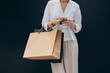 © LUMINA IMAGES - Unrecognisable cropped woman holding shopping bags and typing on her smartphone.