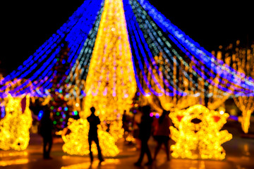 Wall Mural - Closeup blurred and bokeh of Christmas holiday lighting with Silhouette of people in night time background.