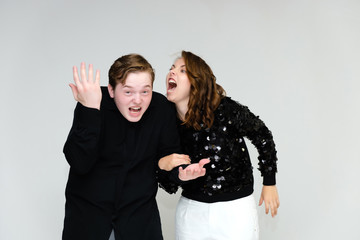 Portrait below the belt on a white background pretty young brunette woman in a black sweater and a young man in a black shirt. Standing in different poses, talking, showing emotions.