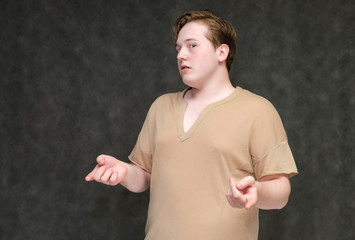 portrait to the waist on a gray background of a handsome young man in a brown t-shirt. stands direct