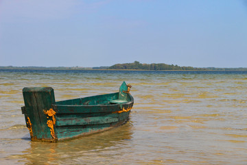 Old vintage wooden green fishing boat on the clear water with horizon