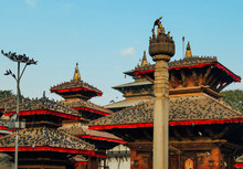 Kathmandu Durbar Square (Basantapur Darbar Kshetra), Nepal. 6 Buildings Visible, Decorated With Red Ribbons. One Pillar In Front Of Them. On Every Rooftop Sit Thousands Of Pigeons. Bright Colors.