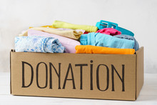 Donation Box With Various Clothes On A Table.