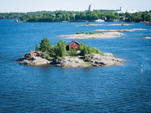 Seascape Of  Scandinavia:  Island With Little Red House In  Baltic Sea. Typical Red Scandinavian Houses On A Rocky Island, Overgrown With Coniferous Trees, Pines. Horizon. Finland Sweden Seascape. 