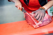 Woman Cutting Fresh Meat In A Butcher Shop With Metal Safety Mesh Glove
