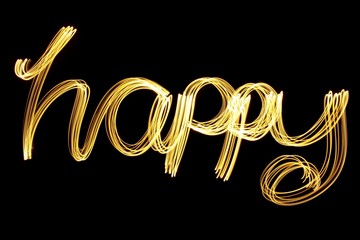 Long exposure photograph of metallic gold colour spelling the word 'happy' against a black background. Light painting photography, happy new year series.