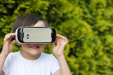 Cute little boy using VR glasses outdoors in a park - Blogger testing augmented reality goggles concept - Gamer exulting during 3D video game playing