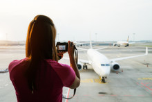 Woman Tourist Shooting Photo In Front Of Airplane At International Airport