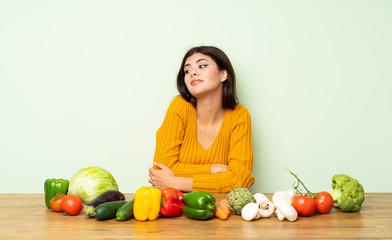 Teenager girl with many vegetables making doubts gesture while lifting the shoulders