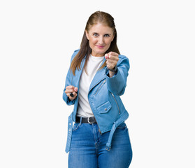 Poster - Beautiful middle age mature woman wearing fashion leather jacket over isolated background Punching fist to fight, aggressive and angry attack, threat and violence