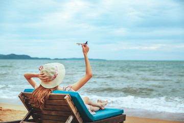 Wall Mural - Asian woman with airplane on sea beach