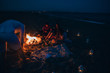 © qunica.com - People sit at night round a bright bonfire on the beach