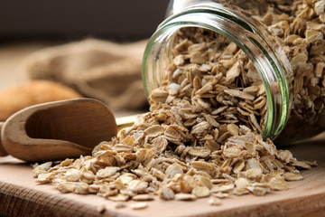 Dry oatmeal flakes in a glass jar on a brown wooden table. healthy nutrition. healthy food. close-up