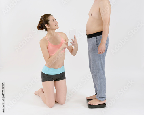 中年太りの男性の体重を量る女性stock Photo Adobe Stock 中年太りの男性の体重を量る女性stock Photo Adobe Stock