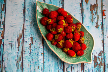 Wall Mural - strawberries on a plate in the form of a sheet on a wooden surface