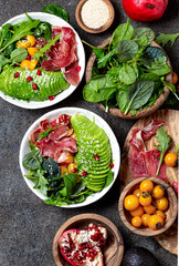 Wall Mural - Low carbs bowl. Fresh salad with green spinach, rucola, avocado an ham serrano in white bowl, gray background, top view