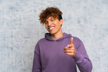 Wall Mural - Young african american man over grunge wall points finger at you