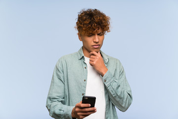 Wall Mural - Young african american man over isolated blue wall thinking and sending a message